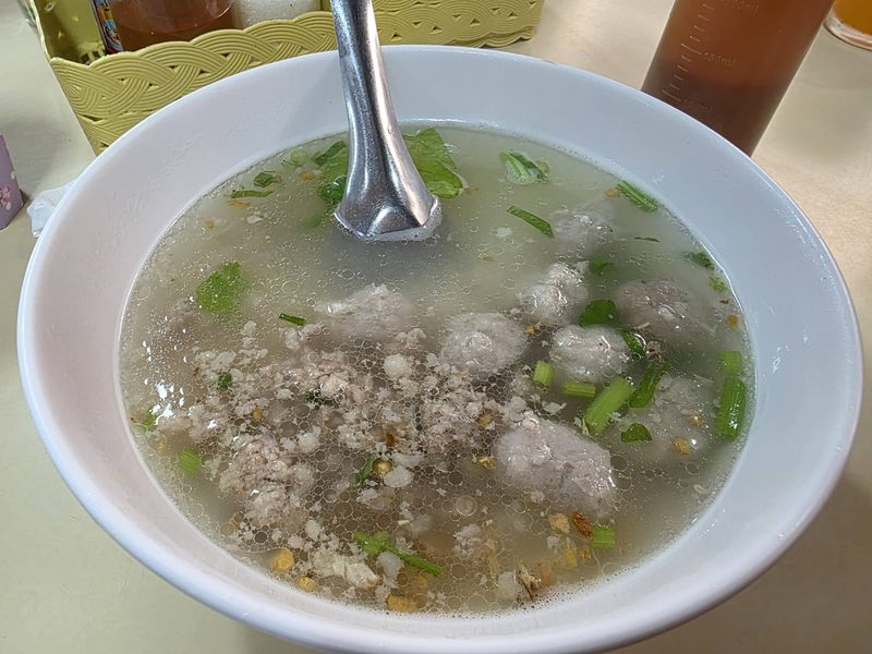 โจ๊กหมูใส่หมูเด้งและต้นหอมในชามขาว